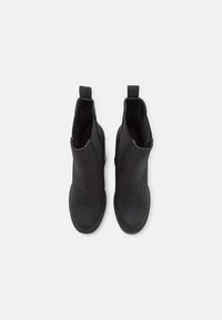 Botines negros de tobillo hechos de material texturizado, con una superficie suave, paneles laterales elásticos y lengüetas para ponérselos fácilmente.
