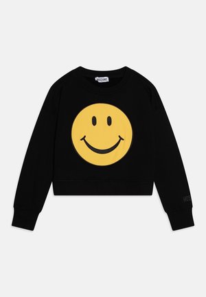 Sort langærmet cropped sweatshirt med stort gult smilende ansigt på fronten og Moschino-logo på kraveetiketten og ærmekanten.