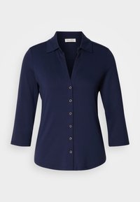 Mørkeblå bluse med trekvartlange ermer laget av mykt stoff, med krage og seks knapper foran.