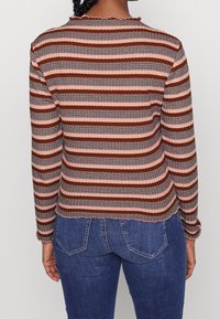 Langærmet stribet top med vekslende brun og lyserød nuancer, med en struktureret mønster og en scalloped halsudskæring.