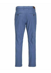 Blå byxor med en slät textur, med två bakfickor med knappstängningar och uppvikta fållar vid vristerna. Brun accent i midjan.