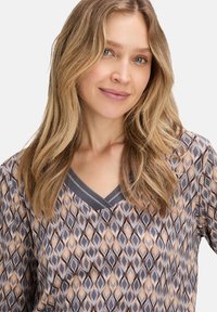 Lightweight patterned top featuring a geometric design in gray, cream, and brown tones, with a V-neck and gray trim. Soft texture.