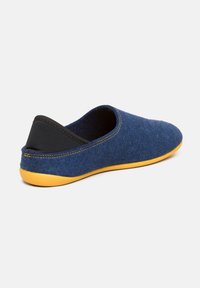 Pantofole blu in feltro con supporto per il tallone nero e suola in gomma gialla. Design a profilo basso con una finitura liscia e testurizzata e cuciture a contrasto.