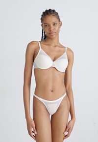 White lace bra with molded cups and thin straps, paired with a matching lace thong. The material is soft with a textured pattern.