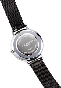 Orologio rotondo con retro in acciaio inossidabile, cinturino in rete nera e dettagli argentati. Presenta testo inciso sul retro della cassa.