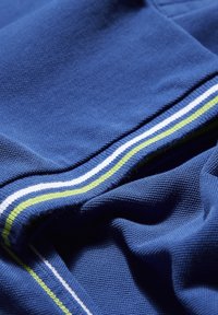 Blått tyg med en strukturerad väv, som har horisontella ränder i vitt och grönt. Kantade kanter är sydda för ett prydligt utseende.