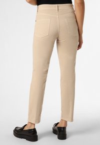 Beiga, figurnära byxor med en slät yta, som har två bakfickor och en medelhög midja. Matchas med svart plattformsskor.