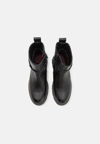 Bottes de cheville en cuir noir avec une finition lisse, bout arrondi, fermeture éclair sur le côté et languette de tirage. Intérieur doublé avec des accents rouges contrastants.