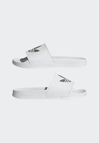 White slide sandals with a textured rubber sole, adjustable strap featuring three black stripes and cut-out detailing. Branded with "adidas" on the side.
