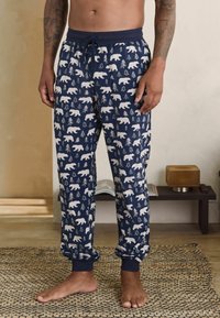 Námornícke pyžamové nohavice s bielym vzorom medveďa a stromov, s elastickým pásom, nastaviteľnou šnúrkou na uťahovanie a s nápletmi na členkoch. Mäkko textúrovaná látka.