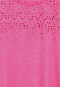 Pink cotton top featuring embroidered eyelet details at the neckline. The texture is smooth with a soft finish.