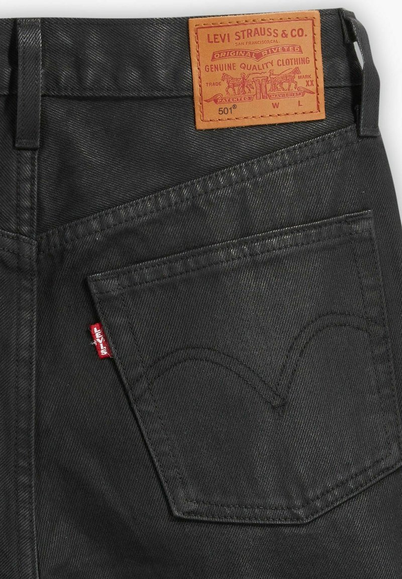 Jean Levi's 501 en denim noir avec une coupe classique, une patch en cuir sur la taille et une petite étiquette rouge sur la poche arrière.