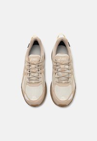 Μπεζ αθλητικά παπούτσια φτιαγμένα από διχτυωτό και συνθετικό υλικό. Περιλαμβάνουν στρογγυλή μύτη, κορδόνια, υφή στη σόλα και λογότυπο στην γλώσσα.