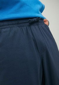 Navy blauwe joggingbroek van zacht materiaal, met een elastische tailleband en een strikkoord, inclusief zijzakken.