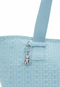 Vaaleansininen kangaskassi, jossa on teksturoitu kuvio, kangasolkaimet ja hopeinen robottihelmi, joka on kiinnitetty renkaaseen.