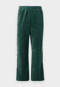 Pantalons de survêtement en velours vert foncé avec une taille élastique, dotés de coutures verticales et de panneaux latéraux blancs avec du texte noir. Coupe droite.