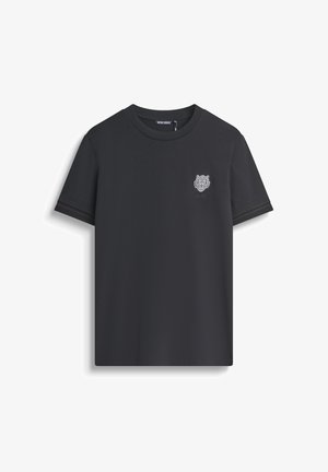 Camiseta de algodón negra con cuello redondo, mangas cortas y un pequeño logo de tigre bordado en el pecho, con sutiles acentos rojos en los puños.