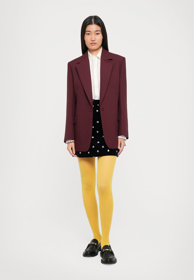 Maroon blazer, white lace blouse, black velvet skirt with floral accents, yellow tights, black loafers with gold hardware.