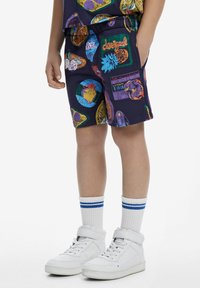Pantaloni corti della marina con fantasie grafiche colorate, vita elastica, tasche laterali, abbinati a sneakers bianche alte e calzini a righe.