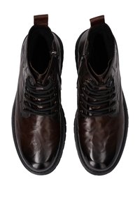 Brązowe skórzane botki za kostkę z błyszczącym wykończeniem, sznurowane z przodu na czarne sznurówki oraz z bocznym zamkiem ułatwiającym zakładanie. Gumowa podeszwa z teksturowanym gripem.