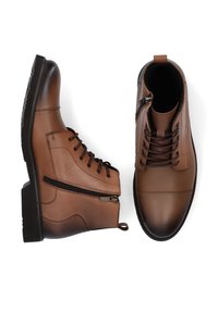 Brązowe skórzane buty z eleganckim designem, splątanymi sznurówkami i bocznym zamkiem błyskawicznym. Podeszwa jest gumowa z właściwościami antypoślizgowymi dla stabilności.