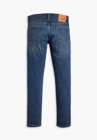 Blå denimjeans med rak bendesign, utrustade med två bakfickor och en läderlogotyp på midjebandet.