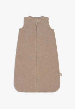 Beige slaapzak met een mouwloos ontwerp, ritsafsluiting en een afgeronde onderkant. Gemaakt van zachte, gestructureerde stof met een logo-label aan de zijkant.