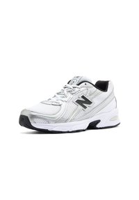 Chaussure de running New Balance blanche et argentée avec des accents noirs, dessus en mesh, lacets et semelle épaisse et coussinée inclinée vers la droite.