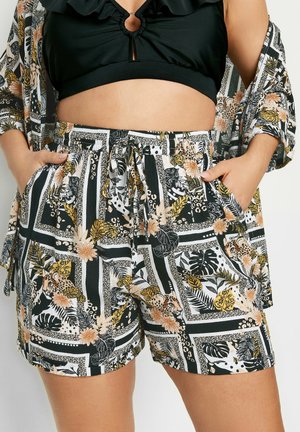 Shorts à motifs noir et blanc mettant en avant des imprimés floraux et animaliers, avec une taille élastique et des poches latérales, fabriqués en tissu léger.