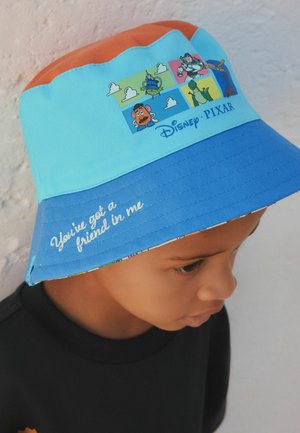 Lapsi, joka pitää värikästä Disney Pixarin ämpärilakkia, jossa on Toy Storyn hahmoja ja reunassa teksti "You've got a friend in me".