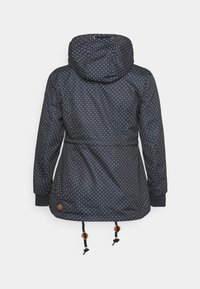 Lång marinblå jacka med huva, täckt av vita prickar. Har elastiska ärmslut, dragsko i midjan och nederkant, samt ett logopatch.