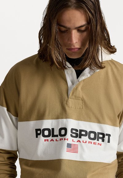 Bruine en witte rugbyshirt met "POLO SPORT" in vet zwart lettertype, een rode accent en een Amerikaanse vlaglogo. Gemaakt van katoen, met een losse pasvorm.