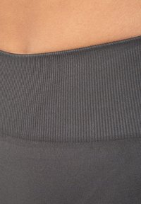 Grijze ribbelstof van een tailleband, gladde textuur met fijne verticale lijnen, naadloos overgaand in de donkerdere stof eronder.