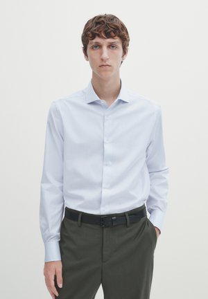 Light blue long-sleeve shirt with a button-up design, paired with dark green trousers and a black belt. Smooth fabric, fitted silhouette.