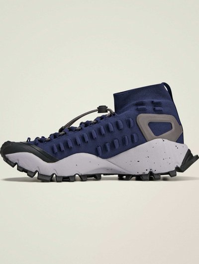 Scarpa da trekking navy con tomaia texturizzata, accenti grigi e design a taglio basso. Presenta una suola in gomma con tappi multi-direzionali per una migliore aderenza.