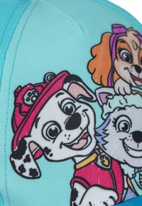 Gorra infantil con una tela azul clara con personajes de dibujos animados, incluyendo un dálmata y otros perros, en colores vibrantes y diseños divertidos.