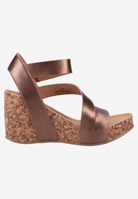 Sandały na koturnie z brązu z korkową podeszwą, ozdobione skrzyżowanymi metalicznymi paskami. Gładka faktura, lekko podwyższony obcas i wyściełana wkładka.
