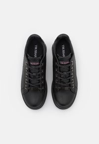 Schwarze Leder-Sneaker mit strukturierter Oberfläche, metallischen Akzenten, kontrastierenden Schnürsenkeln und einem Logo auf der Zunge.