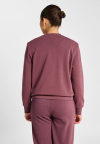Donker mauve sweatshirt met een ronde hals en lange mouwen. Gladde textuur, geribbelde manchetten en zoom. Draagt bijpassende broek.