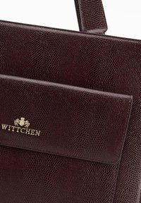 Burgundowa torebka wykonana z tłoczonej skóry o fakturowej powierzchni, z przednią kieszenią i logo z pozłacanym wykończeniem.