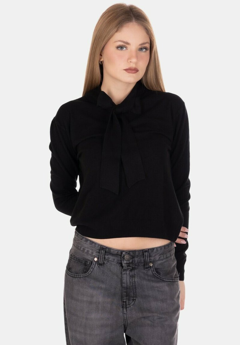 Maglione corto nero con dettaglio del fiocco legato, realizzato in un tessuto morbido. Presenta maniche lunghe e un collo rotondo, abbinato a jeans di denim scuro.