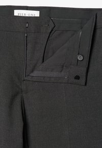 Schwarze, maßgeschneiderte Hose mit glatter Textur, ausgestattet mit einem Reißverschluss, Knopfverschluss und zwei Taschen. Das Etikett trägt die Aufschrift "PIER.ONE."