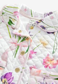 Quilted jakna s belim cvetnim vzorcem v roza, vijoličnih in zelenih tonih; zlatimi gumbi; okroglo ovratnico; in zanko na žepu.