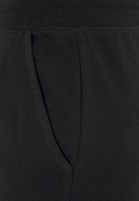 Schwarze Baumwoll-Jogginghose mit geripptem Bund und Seitentasche, rutschiger Textur und sichtbaren Nahtdetails.