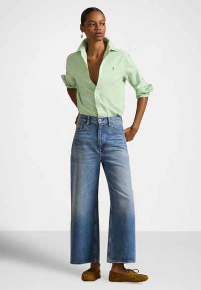 Gaiši zaļa ar apkakli krekls, aizpogāts līdz krūtīm, kombinēts ar plaša piegriezuma gaiši ziliem džinsiem un brūnām mokasīnu kurpēm. Vienkāršs dizains, brīva piegriezuma.