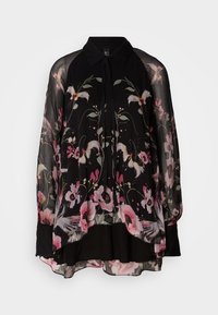 Blouse noire transparente à manches longues, avec des imprimés floraux roses et blancs et un col pointu avec détail de lien à l'avant.