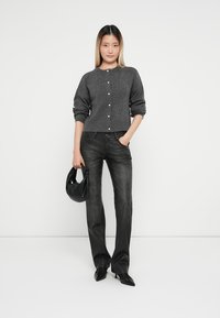 Grå strikkekardigan med rund hals og knappelukking, kombinert med mørke denimjeans og en svart lærhåndveske. Jevn tekstur gjennom hele plagget.