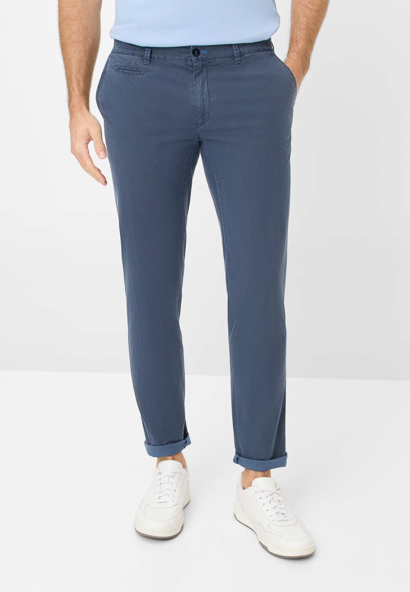 Pantalon bleu marine en matériau léger, design à jambes droites, avec des ourlets roulés et deux poches avant. Assorti avec des baskets blanches.