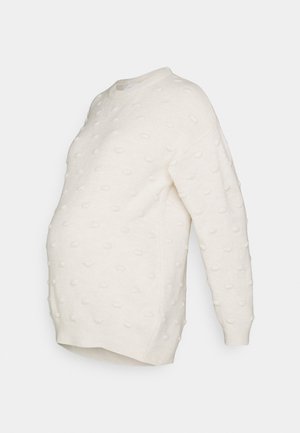 Suéter de maternidad en crema con diseño texturizado de bolitas, cuello redondo, mangas largas y un corte holgado, diseñado para una silueta embarazada.