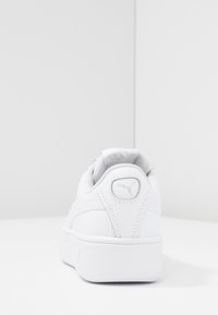Sneaker bianco con finitura in pelle liscia, forma arrotondata, collarino imbottito e un piccolo etichetta con logo sul retro. Suola in gomma texturizzata.